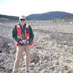 Shelley Inkster, Dena Cho Environmental and Remediation Inc.’s Field Lead, holds a seedling with the crew planting in the background.