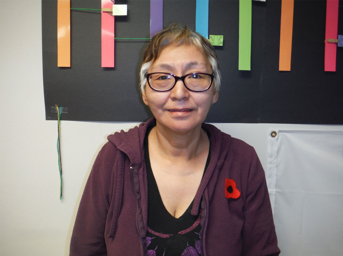 Mayor Meeka Kiguktak sitting in front of a poster with various coloured stripes.