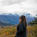 Marilyn looking at a body of water in front of snow-capped mountains.