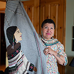 Leena showing a piece of clothing adorned with beadwork and embroidery representing an Inuk woman.