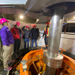ARENA participants wearing hard hats standing around a large power generator.
