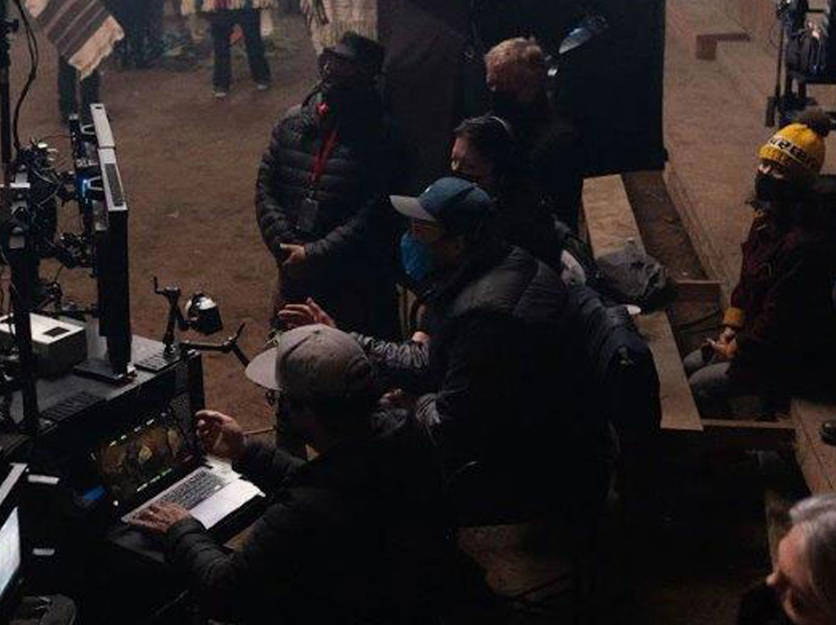 Les acteurs et l'équipe regardent des écrans vidéo sur le plateau.