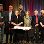 Partners and members of First Nations and Inuit communities in traditional dress standing in front of the memorandum.