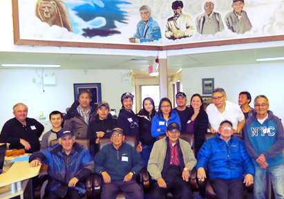 A group picture with four elders sitting on armchairs and the rest of the group standing behind them.